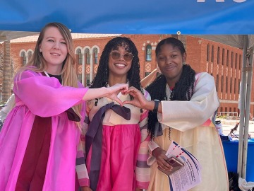 Three students in korean dress making a heart shape with their hands.