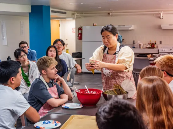 Professor mixing food with her hands at a table of students 